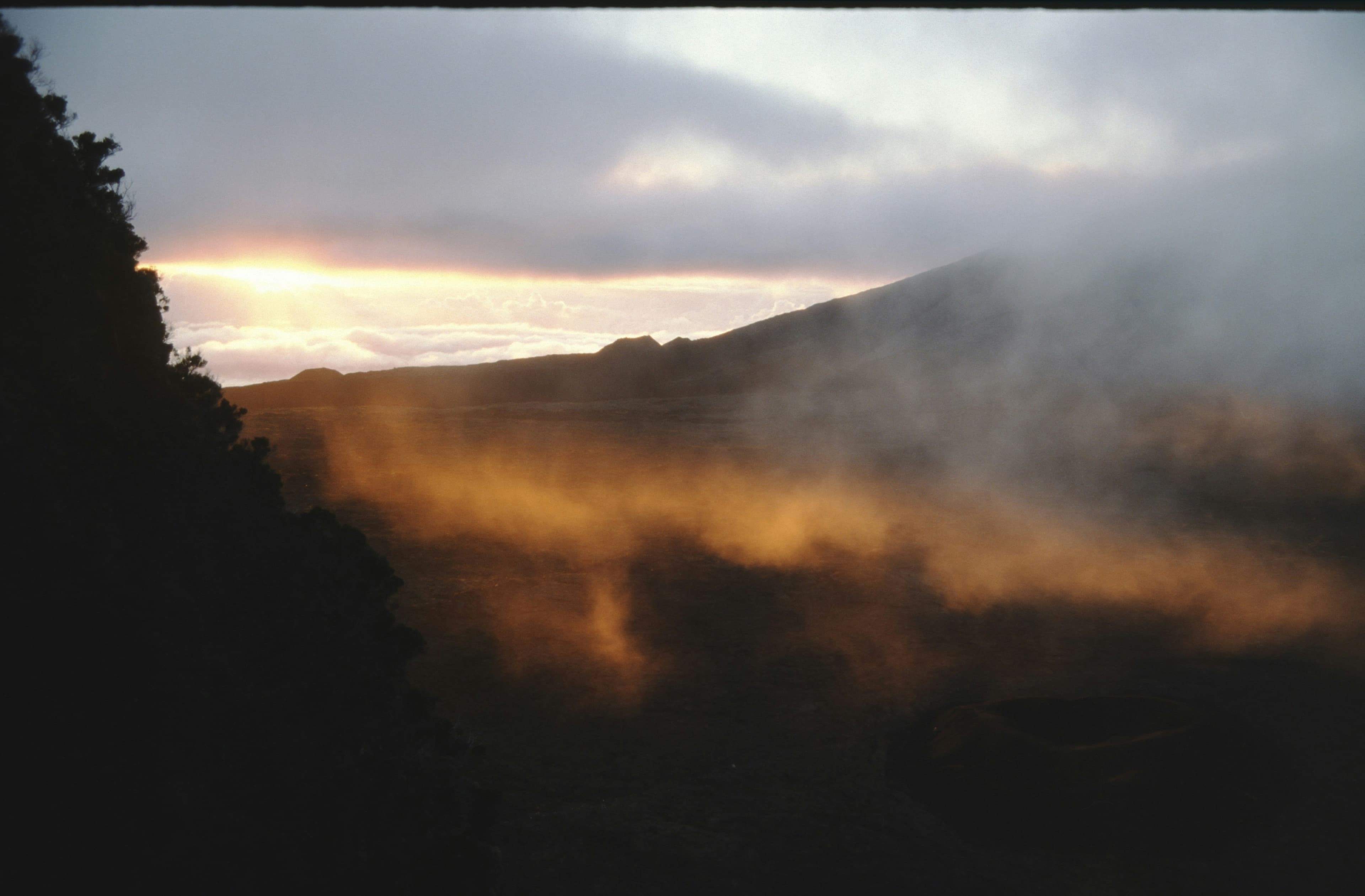 Dramatic mountain cliff edge at sunrise with golden light breaking through storm clouds, new beginnings and breaking free from old patterns
