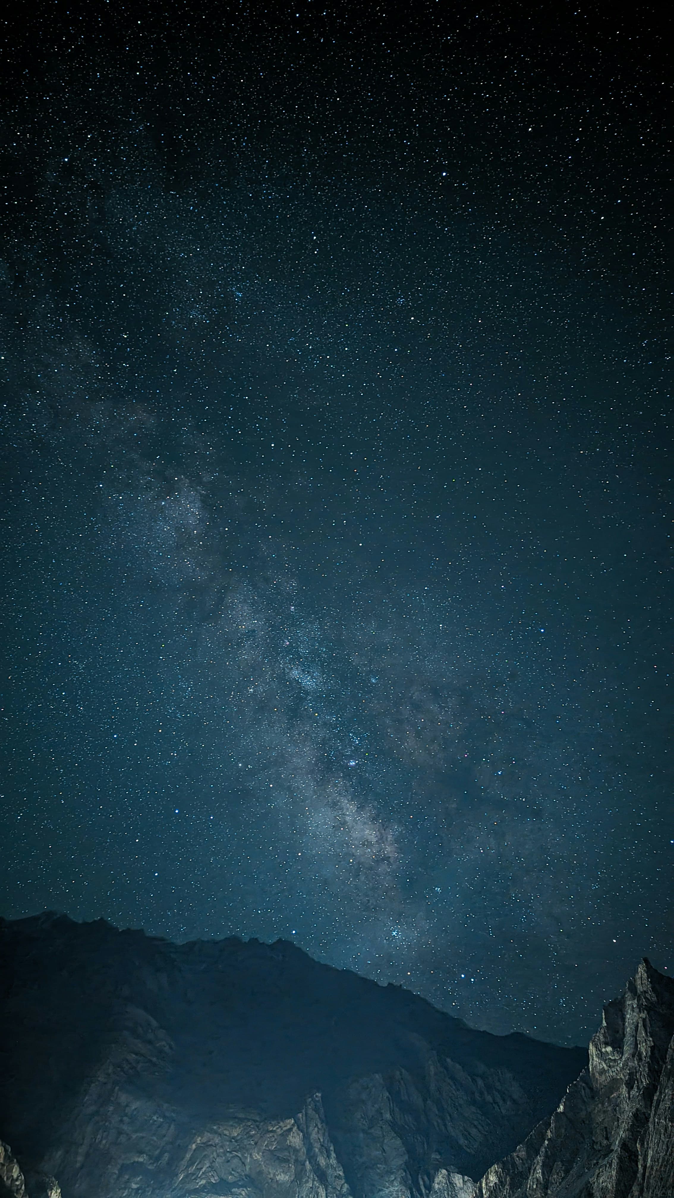 Milky Way over dark mountain silhouettes beneath a deep indigo sky